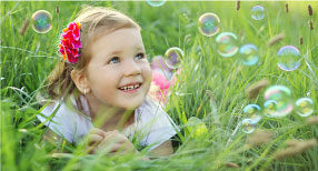 Girl playing with bubbles in grass